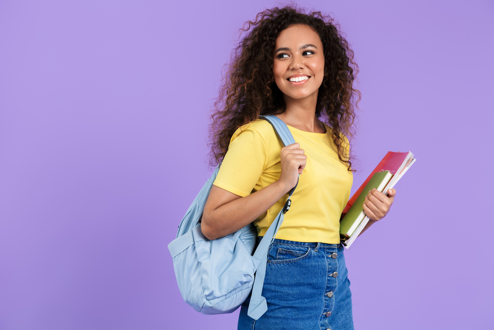 Image of positive african american student girl holding exercise books